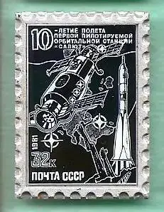Космос (1064). Марка на значке. 10 лет полета 1-й пилотир. орбитальной станции.